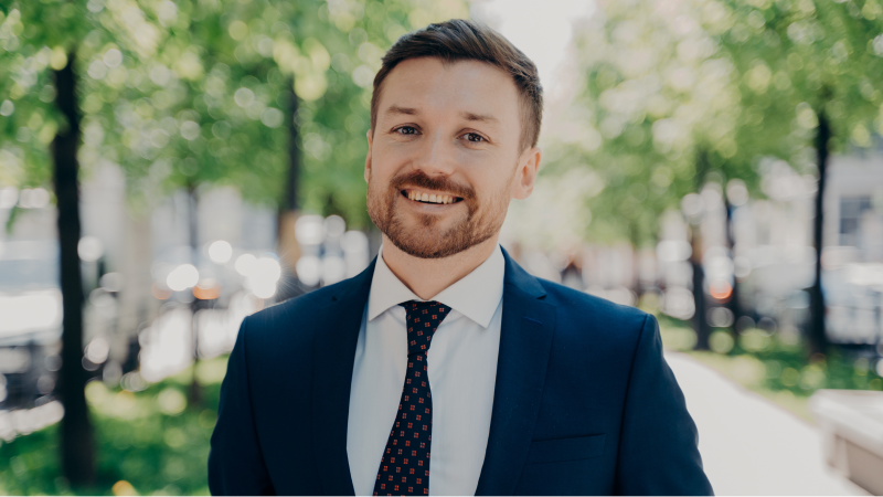 A young businessman dressed in a suit and smiling at the camera