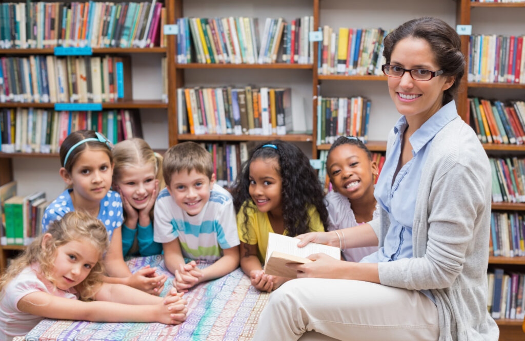 Cute,Pupils,And,Teacher,Reading,In,Library,At,The,Elementary