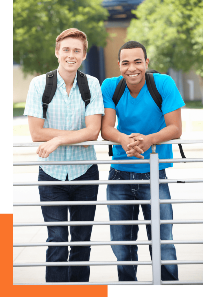 Two young male students smiling outside with backpacks on